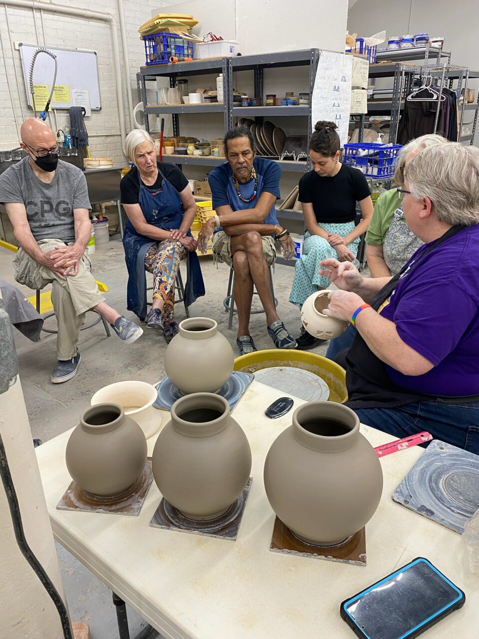 Julia Mann demonstrating in front of students, Moon-shaped vase