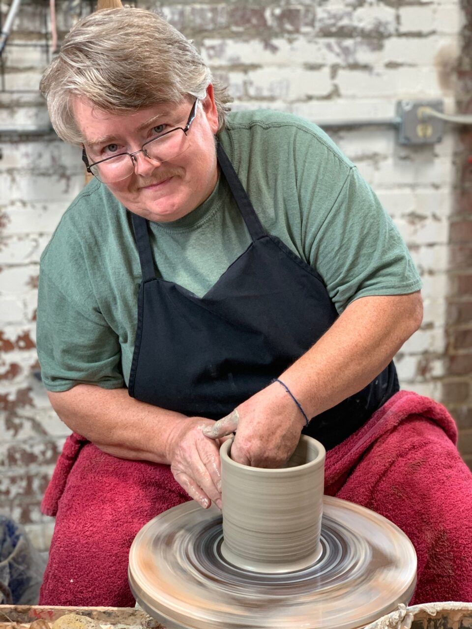 Julia Mann throwing cylinder at potters wheel, smiling