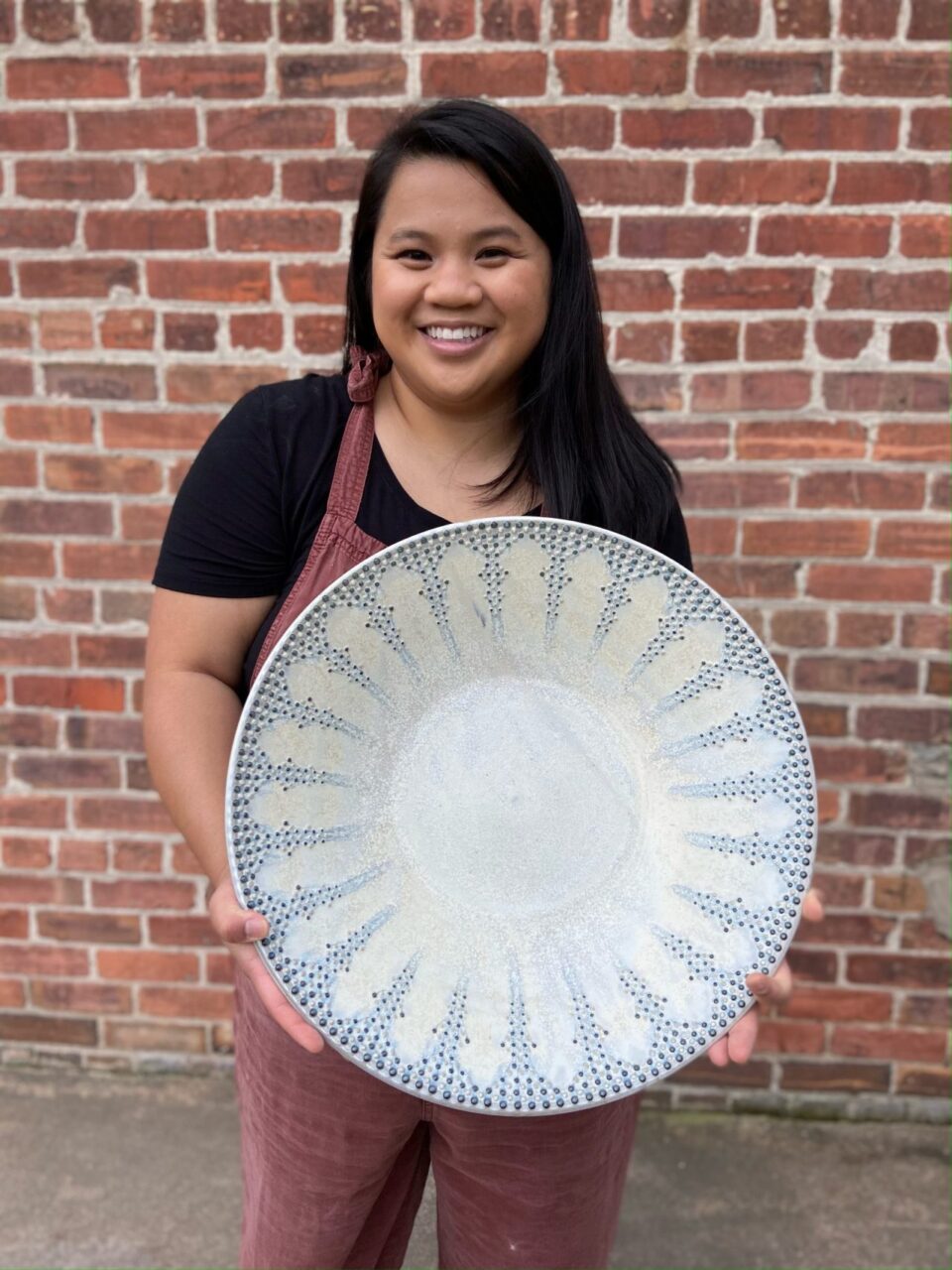 Katie Meili Messersmith holding large statement bowl, dot pots, finished pot, infinite cobalt whispers, smiling