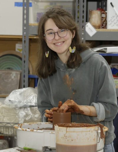 Avery Wells throwing red clay on the potters wheel in community ISM studio