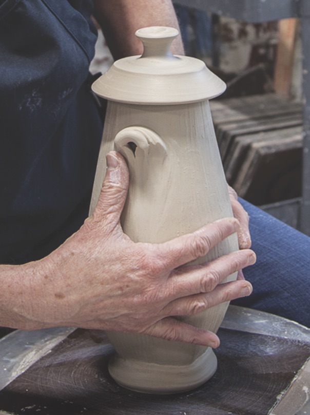 Close up of Sarah Wells Rolland hands sculpting an added handle to a lidded jar