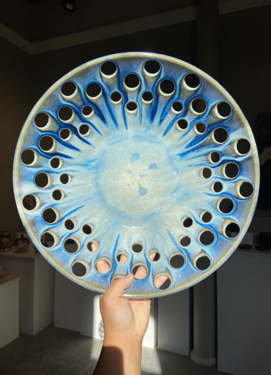 Katie Meili Messersmith low wide bowl with lots of cut outs, sprayed midnight blue glaze, finished pot