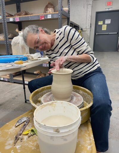 Teaching Center student shaping the rim of her vase, intermediate wheel class